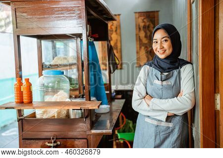 Asian Hijab Woman Wearing Apron Smiling With Hands Crossed