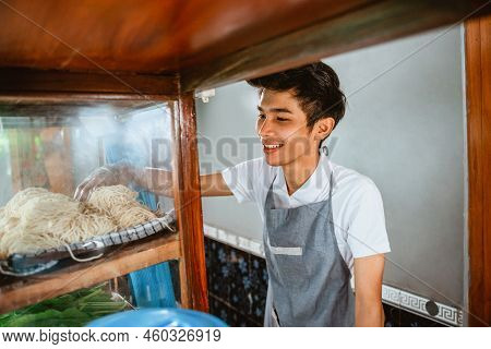 Selling Man Wearing An Apron Takes Noodles While Cooking