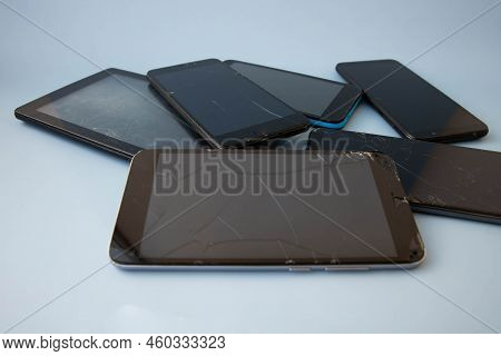 A Lot Of Old Damaged Phones Are Lying On A Blue Background.