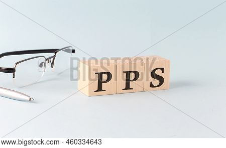 Wooden Cubes With The Word Pps - Pay Per Sale On A Financial Background With Chart, Calculator, Pen 