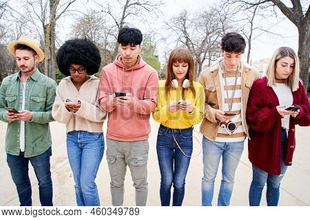 Group Of Young Multiracial Friends Using Smartphone Ignoring Each Other. People And Technology Addic