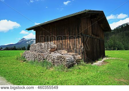 Wooden Shed On A Meadow Under A Blue Sky