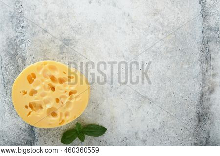 Cheese Maasdam Or Radamer. Piece Of Cheese On Black Marble Or Stone Standa On Old Grey Concrete Back