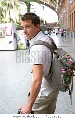 Turista sonriente con la mochila en la estación de tren