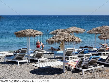 Kamari, Santorini, Greece - June 30, 2021: Sun Loungers On The Black Volcanic Beach Of Kamari In San