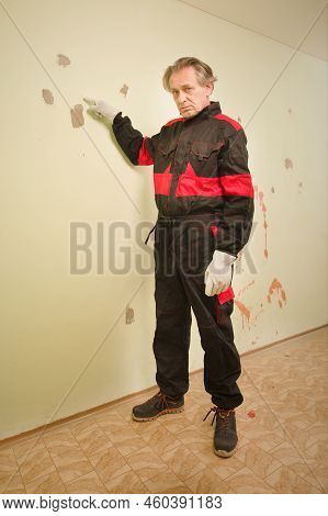 Older Man Working In Empty Apartment Repairing Holes In Walls