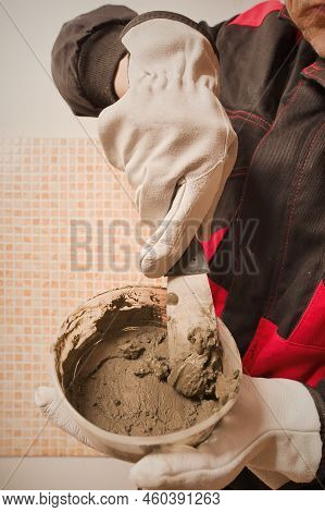 Older Man Working In Empty Apartment Repairing Holes In Walls