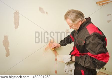 Older Man Working In Empty Apartment Cleaning Dirty Walls