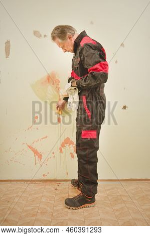 Older Man Working In Empty Apartment Cleaning Dirty Walls