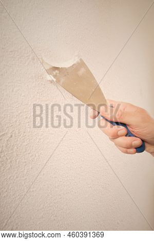 Older Man Removing Old Wallpapers Off The Walls In Empty Apartment