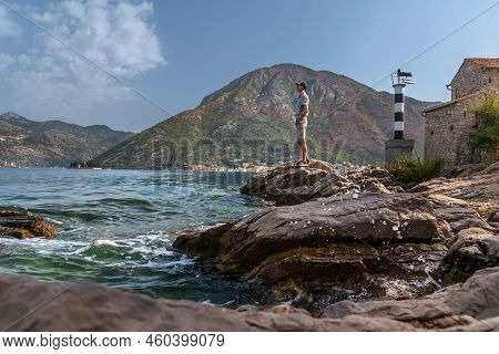 Man Tourists Standing On Cliff Near Lighthouse In Montenegro