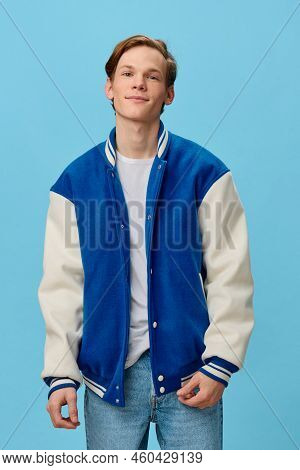 Happy Joyful, Slender Young Man With Red Hair Stands In A Fashionable Blue Jacket And Smiles Broadly