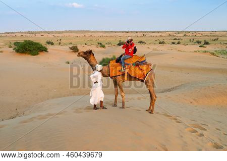 Female Tourist Taking Picture While Riding Camel, Camelus Dromedarius, At Sand Dunes Of Thar Desert,