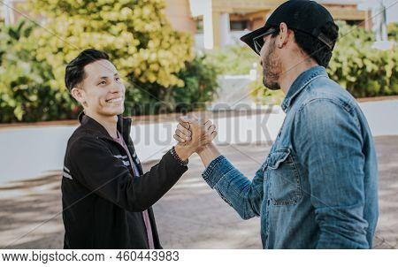 Two People Shaking Hands On The Street. Two Teenage Friends Shaking Hands At Each Other Outdoors. Co