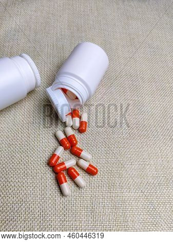 Medicinal Capsules In Gelatin Shell Spilled Out Of Plastic Jar. Medical Pills In Open Upturned Plast