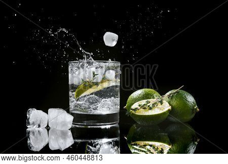 Hard Seltzer With Lime On A Dark Wooden Background, Ice Cubes Fall Into A Glass With An Alcoholic Be