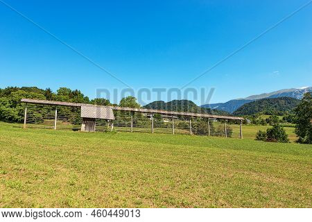 Old Traditional Wooden Barn And Vertical Hay Rack (kozolec - Hayrack) On A Green Meadow, Julian Alps