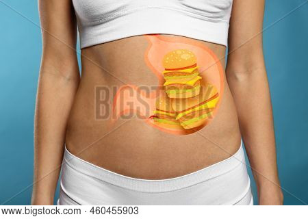 Woman With Image Of Stomach Full Of Junk Food Drawn On Her Belly Against Light Blue Background, Clos