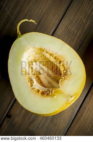 Half A Melon With Bones On A Wooden Table. Seeds Inside A Melon. Part Of The Melon Fruit Is Separate