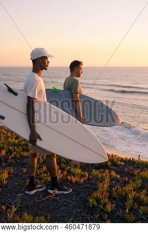 Surfers Watching The Waves At Sunset