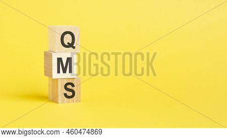 Qms Text On Wooden Block With Yellow Background
