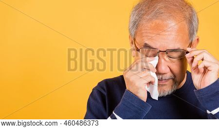Portrait Asian Senior Old Man Sad Wiping Away His Tears Studio Shot Isolated On Yellow Background, E