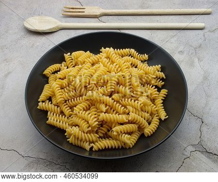 Raw Italian Fusilli Pasta In A Black Dish. Traditional Italian Cuisine.