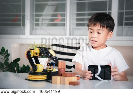 Happy Asian Little Boy Using Remote Control Playing Robotic Machine Arm For Pick Up Wood Block, Funn