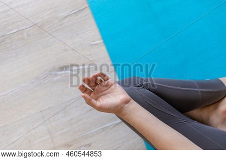High Angle Low Section Of Young Caucasian Woman With Cross Legged Meditating On Blue Exercise Mat In