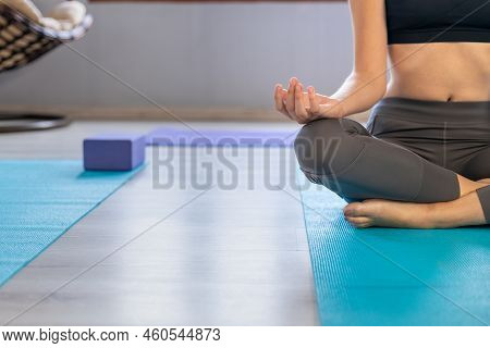 Low Section Of Caucasian Young Woman With Cross Legged Meditating In Lotus Pose On Blue Yoga Mat In 