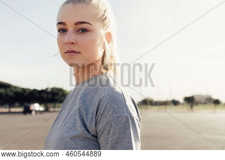Portrait Of Confident Young Female Athlete With Blond Hair Looking At Camera While Standing On Stree