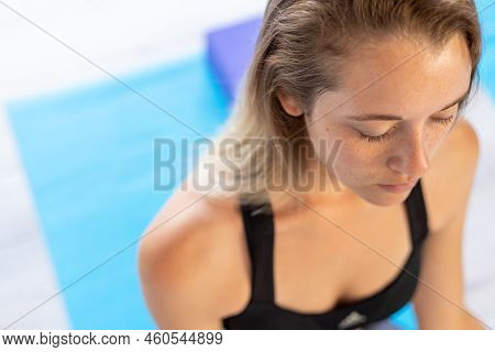 High Angle Close-up Of Beautiful Young Woman With Eyes Closed Practicing Meditation In Yoga Studio