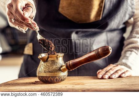 Detail Of A Hand With Spoon And Grounded Coffee Put Into An Ornamented Jezva, Cezve, Or Dzezva.