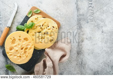 Cheese Maasdam Or Radamer. Piece Of Cheese On Black Marble Or Stone Standa On Old Grey Concrete Back