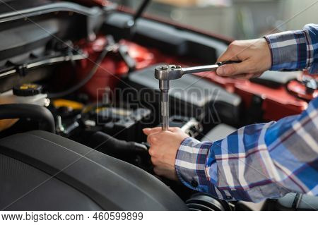 Female Auto Mechanic Unscrewing A Nut To Replace A Car Spark Plug.