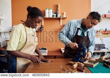 Side View Portrait Of Two Multiethnic Young Women Working With Leather In Workshop And Creating Hand