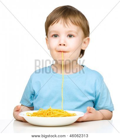 Little boy è succhiare un filamento singolo spaghetti, isolato su bianco