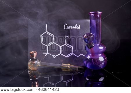 Cannabiol Molecule With Bong And Smoking Pipe With Pipette. Smoking Devices On Black Background.