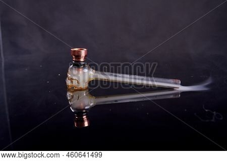 Glass Pipe For Crack Or Crystal Meth On Reflective Mirror Surface. Smoke On Black Background.