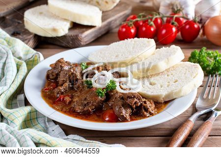 Czech Traditional Goulash With Breaded Dumpling And Onion On White Plate On Wooden Table
