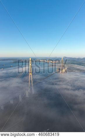 Aerial Shot Of The Mystical Fog Covering The Modern Russian Bridge Over The Sea Strait In The Capita