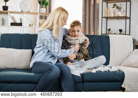 Middle Aged Worried Caring Blond Woman, Mother, Sitting On Sofa At Home, Hugging Her Sick Sad Teen S