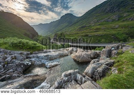 The Setting Sun ,over The Dramatic Valley Of Glen Coe,in Summertime,where Three Small Rivers Meet,at
