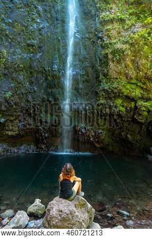 A Young Woman Looking At The Impressive Waterfall At The Levada Do Caldeirao Verde, Queimadas, Madei