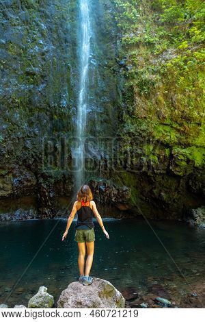 A Young Woman Looking At The Impressive Waterfall At The Levada Do Caldeirao Verde, Queimadas, Madei