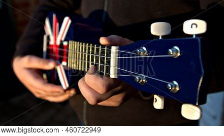 Close Up Of Hands Playing A Red, White And Blue Ukelele