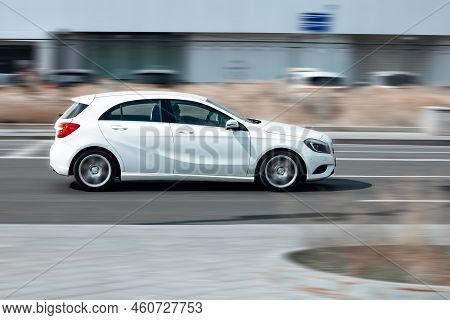 Side View Rolling Shot With White Car In Motion. Mercedes A-class W176 Driving Along The Street In C