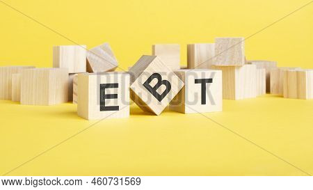 Wooden Blocks With Text Ebt On Yellow Background. Ebt - Short For Earnings Before Taxes