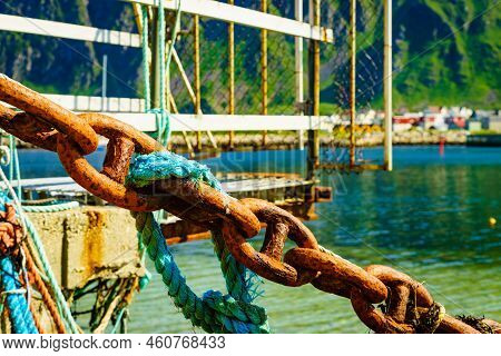 Rusty Old Metal Chain Links In Port. Marine Details. Bleik Village In The Background.