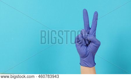Peace Or Good Luck Sign.it Is Hand Gesturing Two Finger On Blue Background.hand Wear Violet Or Purpl